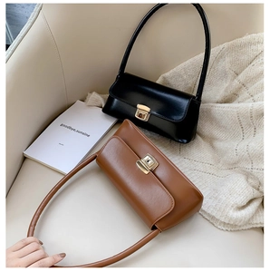 Détail des sacs baguette en cuir noir et marron avec fermoirs métalliques dorés sur canapé