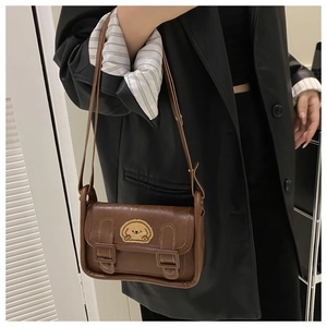 Détail d'un sac bandoulière marron avec broderie chien et doubles boucles rétro