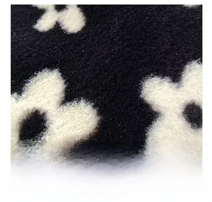 Close-up of soft plush fabric with black and white floral pattern and dense fine fibers