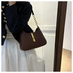Close-up of brown PU leather hobo bag with gold hardware and chain strap on a model