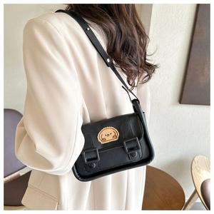 Petit sac bandoulière en cuir noir avec écusson chiot en peluche porté par un mannequin