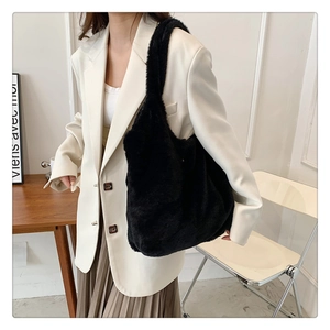Detail of large black plush faux fur shoulder bag worn with a white blazer