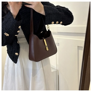 Close-up of dark brown leather handbag featuring unique concave design and gold metal buckle