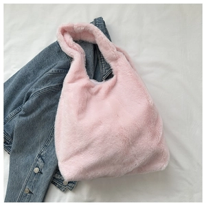 Detailstruktur der weichen rosa Plüschtasche auf weißem Stoff mit einer Jeansjacke dazu