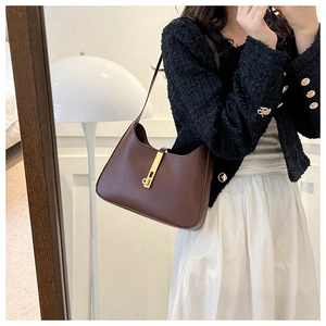 Detail of vintage brown leather underarm bag with gold piston clasp on a model