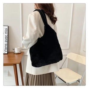 Close-up of fluffy black plush tote bag worn over shoulder for fall winter fashion