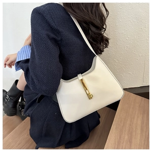 Detail of off-white leather underarm bag featuring a vintage gold metal buckle