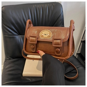 Détail d'un sac bandoulière en cuir PU marron avec broderie chien de dessin animé et boucles