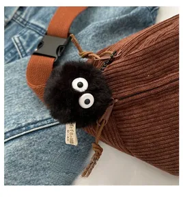 Detail of a fluffy soot sprite plush charm attached to a brown corduroy crossbody bag