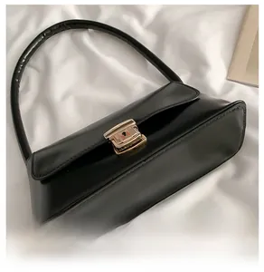 Détail du sac baguette en cuir noir avec un fermoir à boucle en métal doré chic