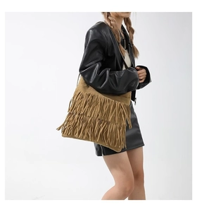 Detail of brown suede shoulder bag featuring long bohemian tassels and vintage style