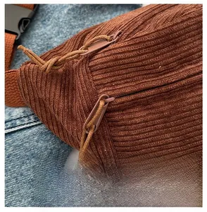 Close-up of brown corduroy crossbody bag with smooth double zippers and woven pullers