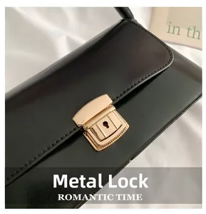 Détail d'un fermoir en métal doré vintage sur un sac baguette noir en cuir brillant