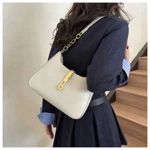 Detail view of cream white leather underarm bag with gold chain strap and metal clasp