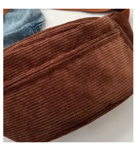 Detailed texture of brown corduroy crossbody bag with vertical ribbed fabric finish