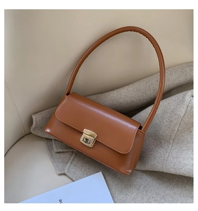 Vue détaillée du sac baguette marron avec boucle dorée sur un canapé beige doux
