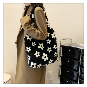 Detail view of large plush tote bag with white daisy pattern on black faux fur