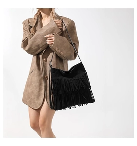Detail view of a black hobo bag with multi-layer fringe tassels worn on a brown blazer