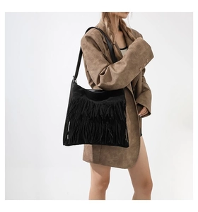 Detailed view of black fringe shoulder bag showing boho tassels and soft suede texture