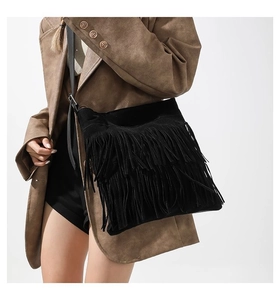 Black suede tote bag featuring fringe details worn by a model in a brown coat