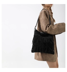 Detail shot of black faux suede tote bag with long bohemian tassels and thin strap