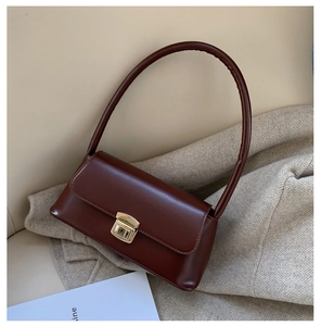 Détail d'un sac à main vintage en cuir marron avec boucle dorée sur un blazer beige