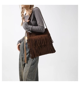 Detail of dark brown suede tote bag featuring bohemian fringe and premium matte texture