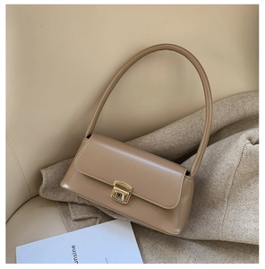 Détail d'un sac sous le bras rectangulaire beige en cuir avec fermoir en métal doré