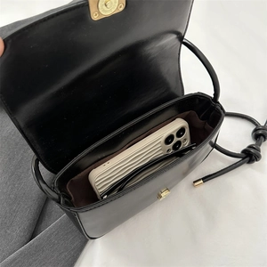 Sac à bandoulière en cuir noir montrant la capacité pour smartphone et lunettes de soleil