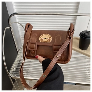 Détail d'un sac bandoulière vintage marron avec broderie chiot et texture PU mate