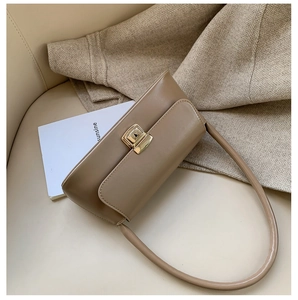 Détail du sac sous le bras en similicuir marron clair avec boucle en métal doré