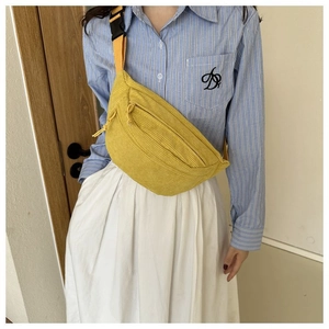 Detail of yellow corduroy crossbody bag featuring zipper closure and nylon strap