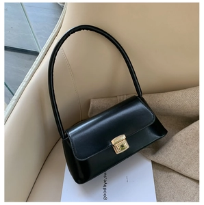 Gros plan d'un sac baguette minimaliste en cuir noir avec un fermoir en métal doré