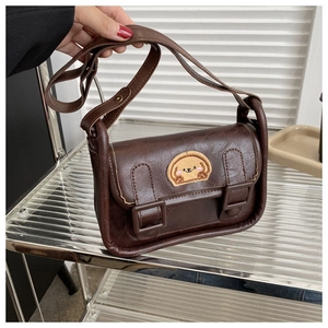 Détail du sac à bandoulière marron en similicuir avec un écusson brodé de chiot mignon