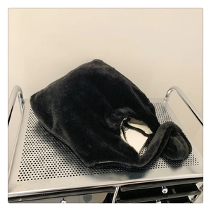 Detail of a black plush handbag on a silver metal cart showing soft faux fur texture