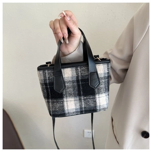 Dettaglio della mini borsa tote in tela a scacchi con manico in pelle e tracolla nera