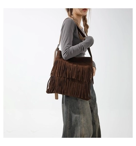 Detailed close-up of brown suede shoulder bag featuring long bohemian style double tassels