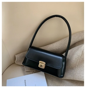 Vue macro d'un sac à bandoulière en cuir noir mat avec boucle en métal doré élégante