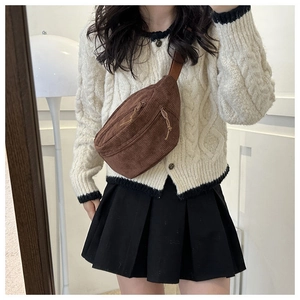 Close-up of brown corduroy crescent bag shown with casual knitwear on a model