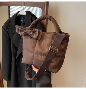 Détail d'un sac matelassé marron avec noeud latéral et bandoulière tissée réglable