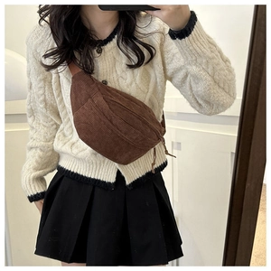 Close-up of a brown corduroy crescent chest bag worn across a model knit sweater