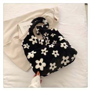 Close-up of fluffy black and white floral plush shoulder bag with soft faux fur texture