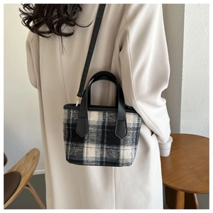 Modella che indossa una piccola borsa tote a scacchi bianchi e neri su un trench, vista cross