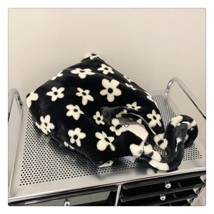 Detail of plush faux fur tote bag with black and white floral pattern on a metal cart