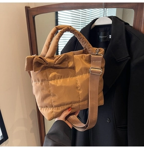 Gros plan du sac en duvet matelassé caramel avec grand nœud et poignée supérieure
