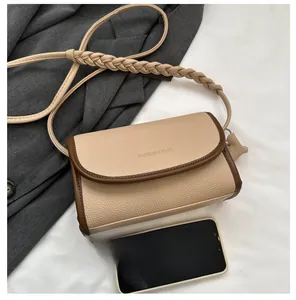 Detailed view of beige crossbody bag with pebbled leather texture and thick woven strap