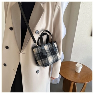 Modella che indossa una mini borsa a quadri con manici in pelle nera e dettaglio tracolla