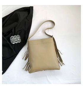 Detail of vintage beige tote bag featuring stylish side tassels and wide shoulder strap