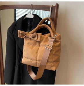 Détail du sac matelassé marron avec grand nœud et bandoulière en tissu réglable