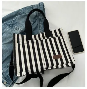 Détail du sac cabas rayé avec bandoulière et smartphone pour référence de taille